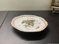 Front view of octagonal ceramic plate featuring flower and butterfly motif and gold decorative rim.