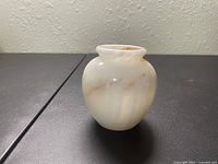 Front side view of vintage small vase showing rounded shape and creamy color with natural swirls.