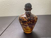 Close-up of the vintage tortoiseshell patterned glass bottle with a rounded stopper, showing the detail of the glass and pattern.