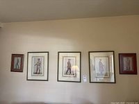 Five framed prints hung in a row on wall, three large in middle, two smaller on ends