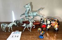 Overview of six animal figurines: bronze-look Flying Horse on wooden base, three small silver-tone horses, colorful elephant and rooster figurines