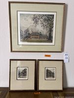 Three framed and matted art prints hung on a wall: one larger print above two smaller prints.