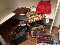 Various bags placed on shelves and floor including leather, fabric, canvas, and faux-croc handbags and satchels