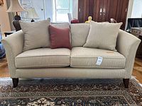 Front view of cream herringbone loveseat with three pillows