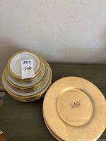 Stack of plates with gold ornate detailing showing bottom marks.