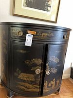 Front view of black lacquer chinoiserie half-moon cabinet with drawer and doors