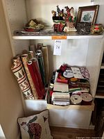 Full view of shelf containing assorted Christmas ribbons, partial rolls of wrapping paper, bags, and some decorative items.