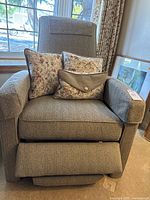 Front view of recliner with footrest extended, showing texture and pillows.