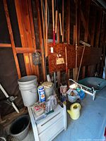 Wide view of all gardening tools, buckets, wheelbarrow, and supplies organized near a wooden wall.