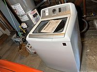 Front angled view of the white GE top loading washer with visible control panel and lid.