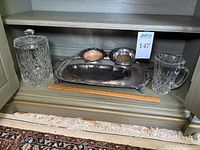 Full view showing cut glass biscuit jar, two silver plate wine holders, and two silver platters with a glass pitcher