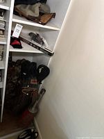 Golf bags in corner with assorted golf clubs, mainly irons and woods visible, leather and fabric bags in used condition showing wear