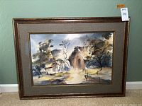 Full view of the matted and framed watercolor painting, showing the landscape scene with a barn and windmill, set against a grey-green wall.