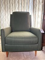 Front view of green upholstered armchair on wood legs