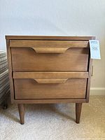 Front view showing two drawers, integrated handles and tapered legs