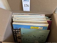 Box of vintage record albums showing a range of sleeve colors and thicknesses packed tightly in a cardboard box.