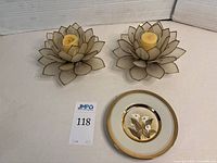 Photo showing two lotus flower candle holders made of capiz shell with a small decorative plate featuring calla lilies in front.