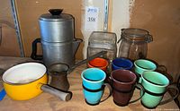 Full view of vintage kitchenware items including cups, pot, percolator, melter, and canister arranged together