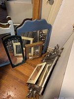 Seven assorted mirrors arranged leaning against walls and furniture showing variety of frames and sizes