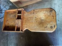 Top view of the wooden bench showing the rounded seating surface and multiple compartments for storage.