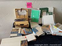 Wide shot showing wooden easel, multiple brushes, various sized gesso boards and canvas packs, some stacked and some in packaging.