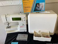 Overview of Bernina 1530 sewing machine, carrying case, bobbin set, presser feet box and pattern booklet