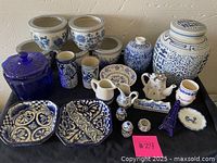Full view of all blue and white ceramic items including pots, plates, teapot, and decorative souvenirs.