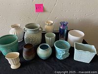 Photo showing assortment of 12 various vases and pots in blue, white, green, and purple colors with varied shapes and decorative elements.