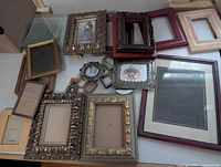 Overview of multiple wooden and metal picture frames in various sizes and styles spread out on a surface.