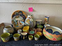 Wide view showing entire colorful Mexican style ceramic dish set including bowls, plates, jars, mugs, and serving ware
