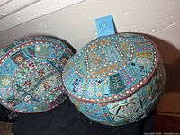 Two round poufs placed on black fabric, showing overall shape and pattern