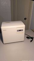 White Seiko HB-12W bread maker on table with visible control panel and power cord.