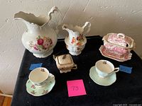 Overview photo capturing the two porcelain pitchers, teacups with saucers, soup tureen, and covered sugar bowl arranged on a table.