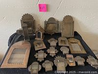 Multiple tin shadow box frames in various shapes and sizes arranged on table