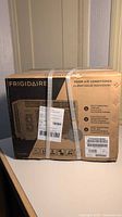 Sealed Frigidaire FFRA051WAE room air conditioner box with labels and straps visible, showing product branding, features and model number.
