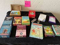 Wide view of all oracle and tarot card decks, two crystals and wooden box on black cloth