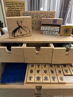 Top view of one wooden drawer set showing rubber stamps arranged on top and alphabet and word drawers partially open with stamps visible inside.
