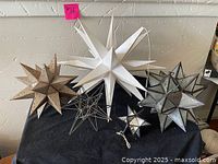 Overview of six star ornaments displayed on black cloth against a wall, showing size and design variety