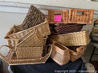 Overall photo showing a stack of various square and rectangular woven baskets in natural brown tones.