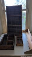 Large wooden storage organizer with many small individual compartments arranged in a grid, showing front view with natural wood color and visible wear.