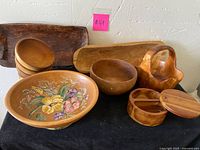 Various wooden serving dishes including bowls, serving trays, a basket, and a lidded container arranged on a table
