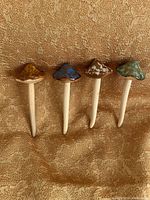Front view of four ceramic mushroom stakes lined up
