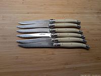 Six Laguiole steak knives on bamboo surface