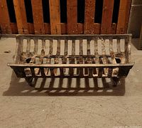 Front view of cast iron fireplace grate showing slotted front and integrated feet