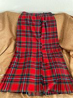 Full view of red tartan wool kilt laid flat showing pleats and length