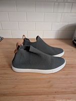 Side view of both grey slip-on rain boots showing knit uppers and white soles