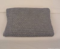 Folded hand knit wool blanket laid flat