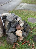 Pile of assorted medium to large landscaping rocks beside utility pole