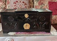 Closed chest showing carved bamboo motifs and brass hardware
