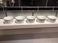 Five matching gold-rim ramekins on windowsill